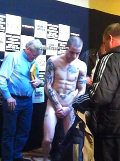 The heavily tattooed tough guy demurely stands on the scales covering his cock and balls