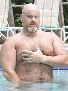 Burly bald bear Brick Hampton takes a dip in the pool naked and massages his cock
